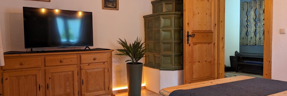 Wohnzimmer im Ferienhaus Wiesenhof in Klais mit traditionellem Holzofen und moderner Beleuchtung.