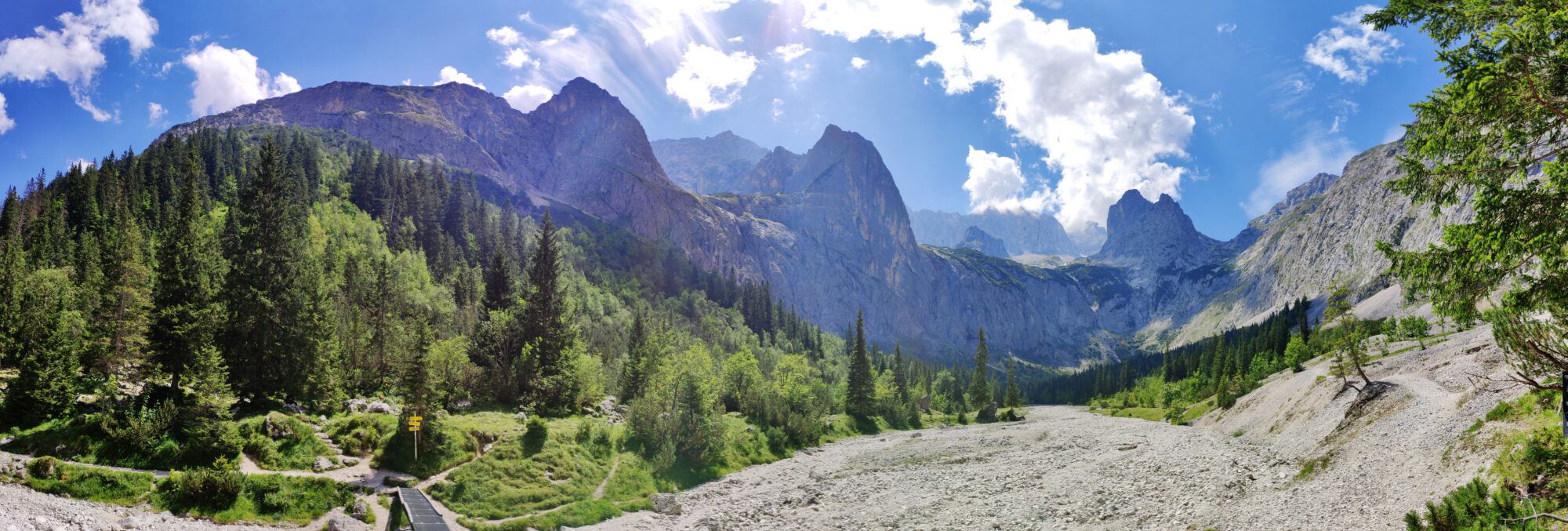 Panoramablick auf die Höllentalklamm und die umliegenden Berge unter einem klaren blauen Himmel.