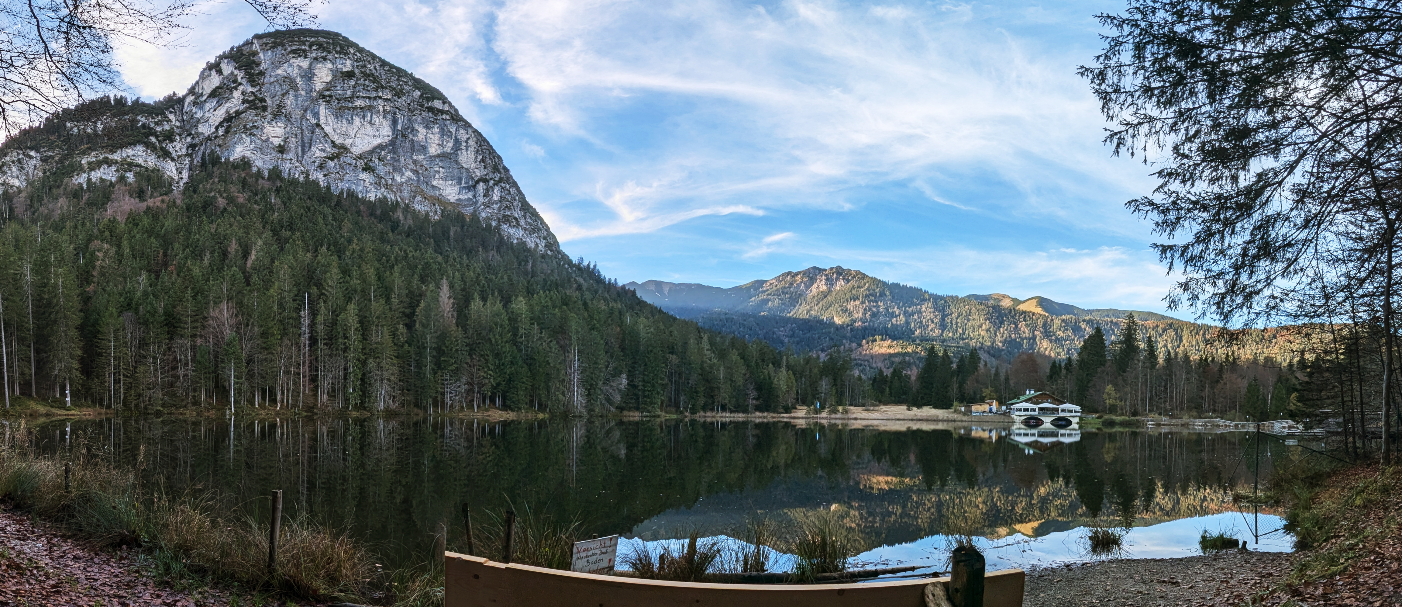 Panorama des Pflegersees im Herbst, umgeben von Wäldern und Felswänden.