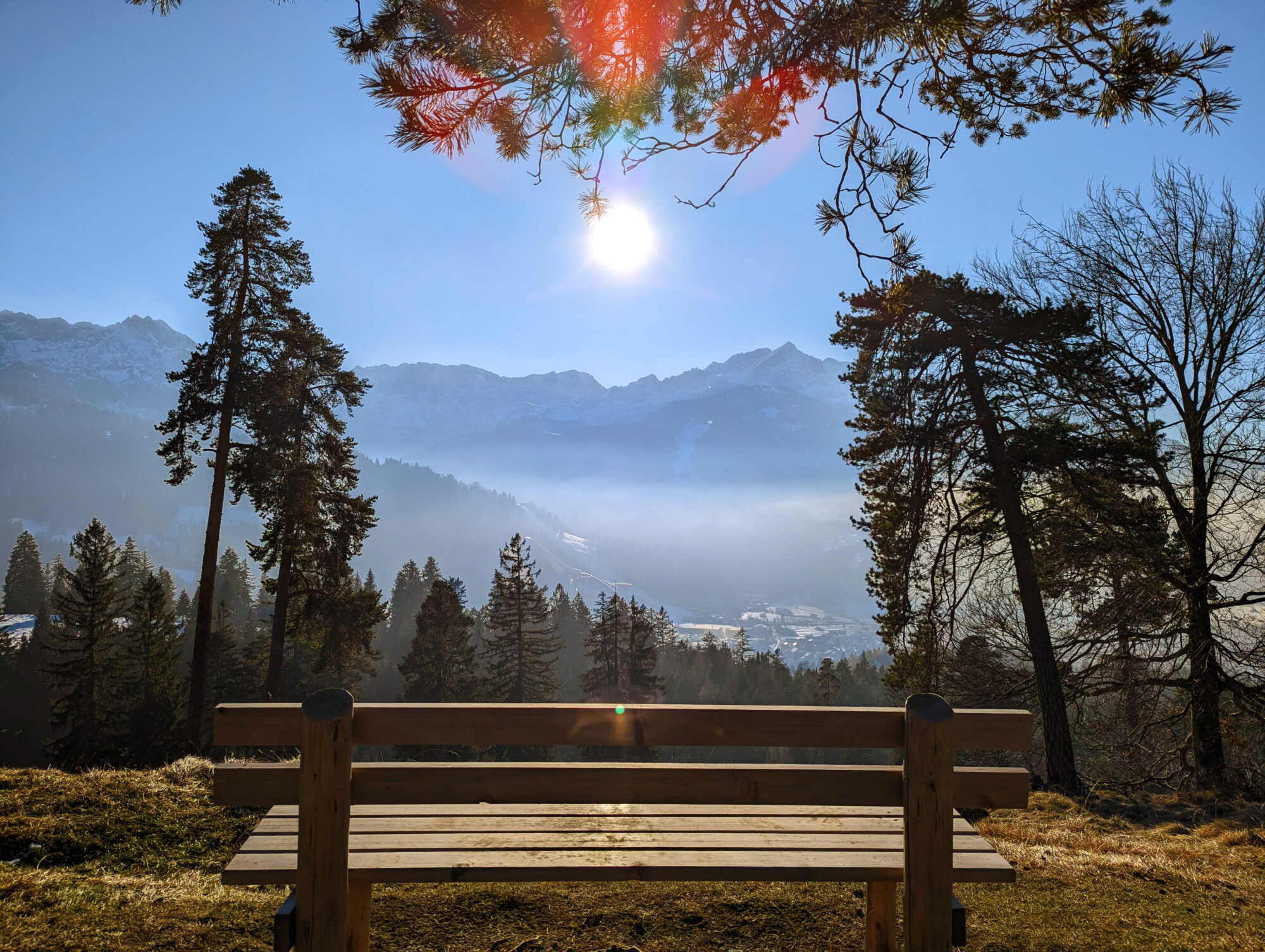 Holzbank auf einem sonnigen Weg zur Tannenhütte mit Blick auf die Alpspitze in Garmisch-Partenkirchen
