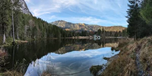 Panorama des Pflegersees im Herbst, umgeben von Wäldern und Felswänden.