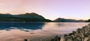 Sonnenuntergang über dem Walchensee mit rosa-goldenem Himmel und ruhiger Wasseroberfläche