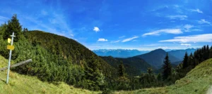 Panoramaaufnahme vom Heimgarten mit Bergwiese, Wegweiser und Blick auf Karwendelgebirge