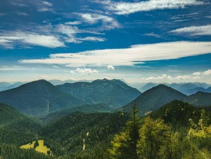 Blick vom Heimgarten über bewaldete Hügelketten Richtung Alpen
